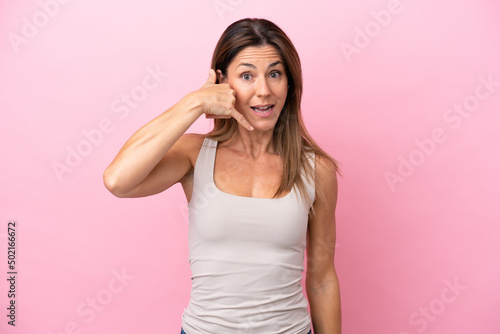 Middle age caucasian woman isolated on pink background making phone gesture. Call me back sign