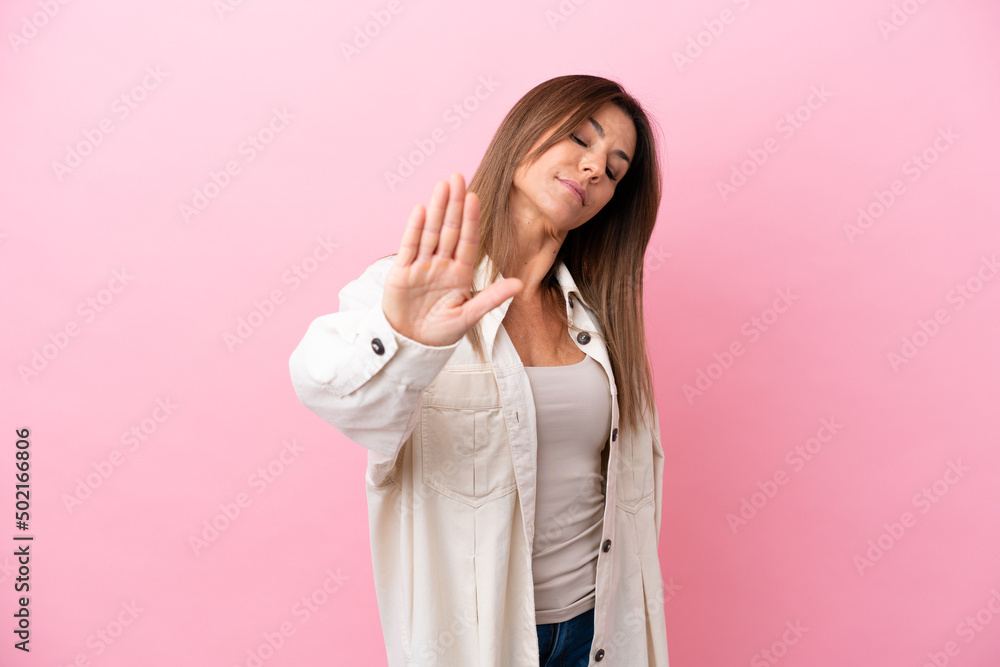 Middle age caucasian woman isolated on pink background making stop gesture and disappointed Middle age caucasian woman isolated on pink background making stop gesture and disappointed