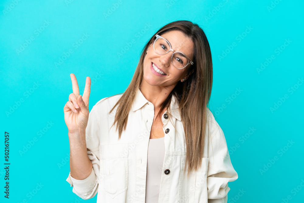 Middle age caucasian woman isolated on blue background With glasses and doing OK sign Middle age caucasian woman isolated on blue background With glasses and doing OK sign