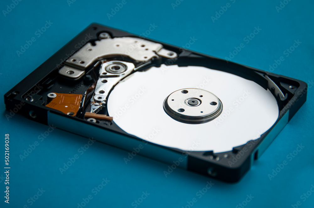 The abstract image of inside of hard disk drive on blue cover background. Concept of data, hardware, and information technology. The abstract image of inside of hard disk drive on blue cover background. Concept of data, hardware, and information technology.