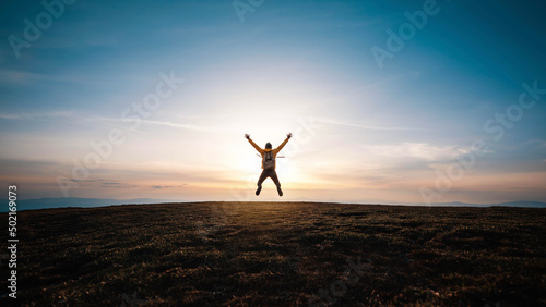 Happy man with open arms jumping on the top of mountain - Hiker with backpack celebrating success outdoor - People, success and sport concept