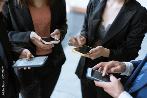 A Group of young businesspeople standing and using smartphones together concepts communication. 