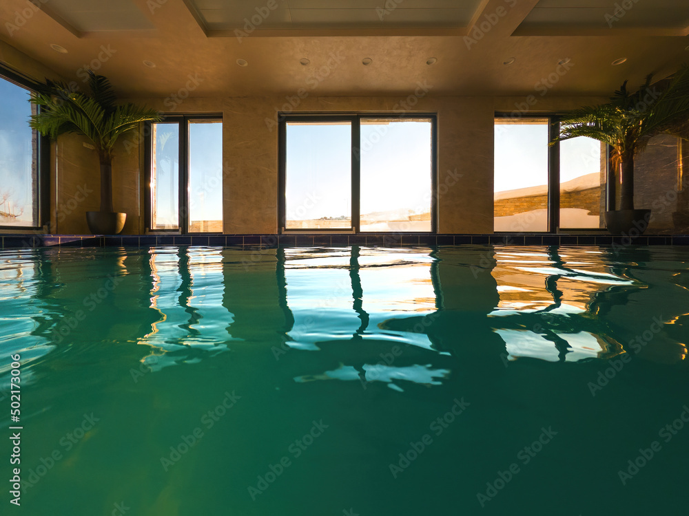 Empty indoors swimming pool with emerald green water