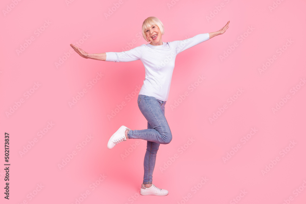 Full length photo of cheerful senior lady have fun hands balance wear casual outfit isolated over pink color background Full length photo of cheerful senior lady have fun hands balance wear casual outfit isolated over pink color background