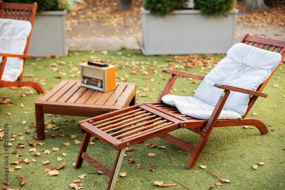 Lounge sunbed. Wooden garden furniture on grass lawn outdoor for relax. Backyard exterior. Wooden chairs in autumn garden. Vintage radio on table. Two deckchairs on green summer lawn on picnic. Lounge sunbed. Wooden garden furniture on grass lawn outdoor for relax. Backyard exterior. Wooden chairs in autumn garden. Vintage radio on table. Two deckchairs on green summer lawn on picnic.