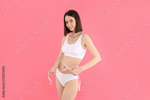 Concept of weight loss, young woman on pink background