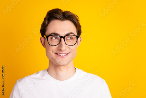 Photo of young wondered man look empty space thoughtful plan eyewear isolated over yellow color background