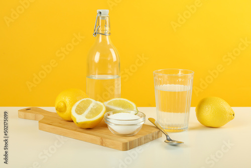 Composition with household cleaners on white table against yellow background