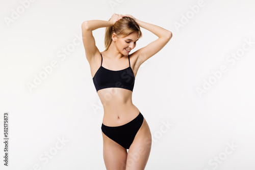 Girl with beautiful muscular body in black lingerie. Photo of smiling girl with perfect body. Fitness or plastic surgery concept