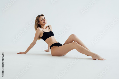 young beautiful woman with perfect body in black underwear sitting on floor on white background © F8  \ Suport Ukraine
