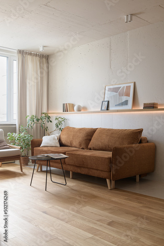 living room in modern studio apartment, brown sofa in the living room, loft style interior