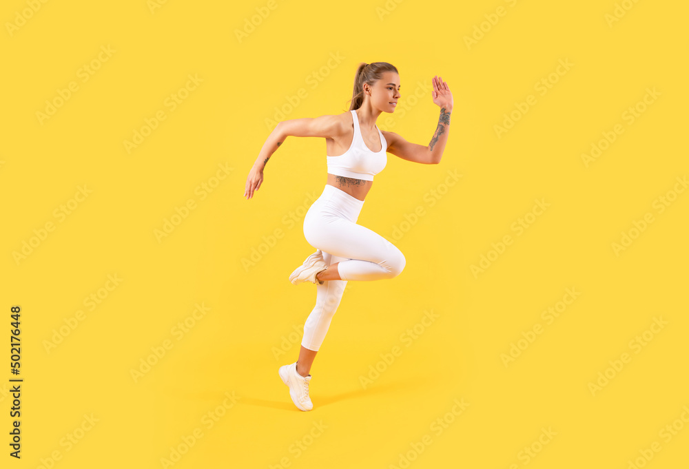 fitness girl jumping in sportswear on yellow background