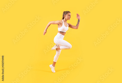 fitness girl jumping in sportswear on yellow background