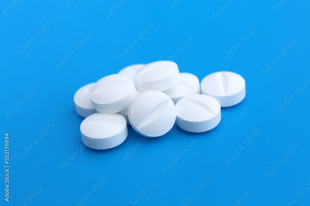 White drug pills lie on a blue background,
