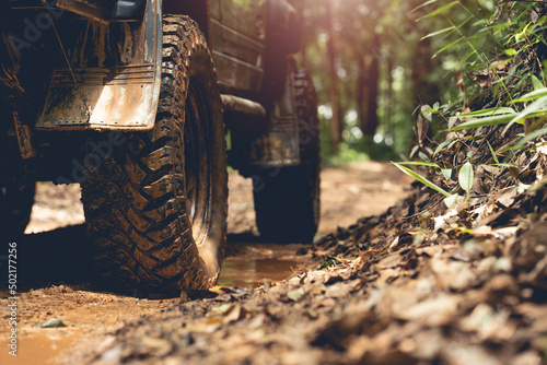 Part of an off-road vehicle on a dirt road with warm light. Adventure concept.Tire off-road on mud	 photo