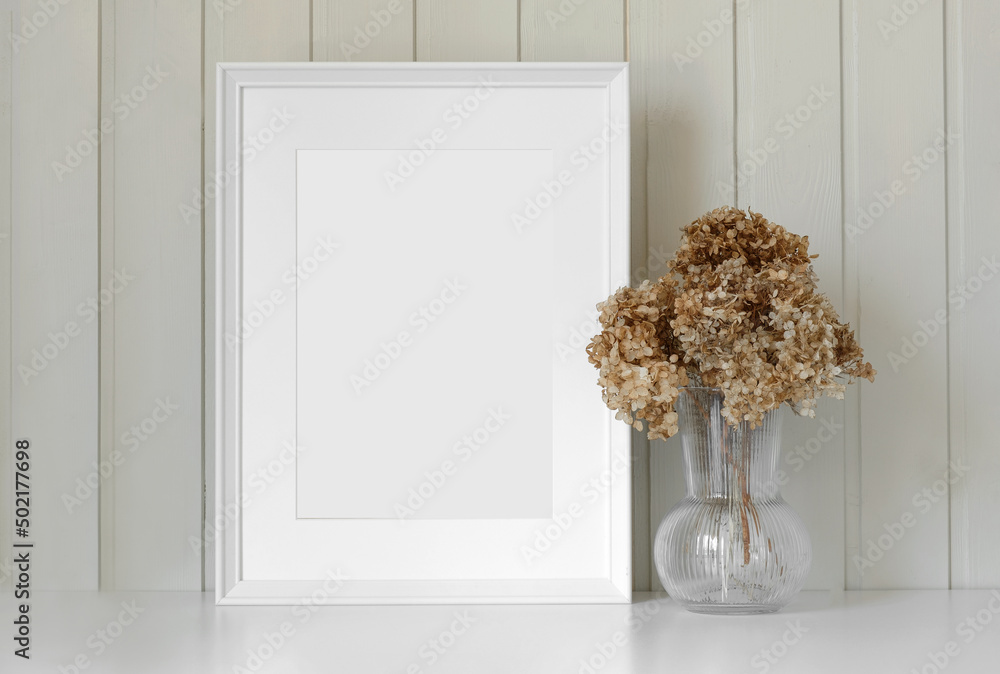 Empty picture frame with beautiful bouquet of dried hydrangea flowers. Modern white ceramic vase with dry grass. Wooden wall background. Elegant Scandinavian interior. Summer, fall still life photo Empty picture frame with beautiful bouquet of dried hydrangea flowers. Modern white ceramic vase with dry grass. Wooden wall background. Elegant Scandinavian interior. Summer, fall still life photo