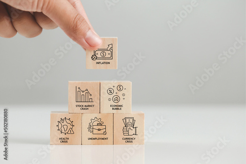 Hand arranging wood block stacking with inflation icons. Causes and consequences of financial crises. stock market crash economic bubble economic crisis health crisis unemployment currency crisis.