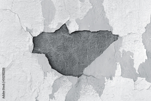 The wall is peeling gray paint with a hole in the middle © денис климов