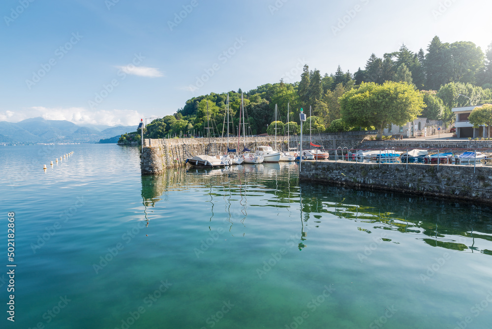 Typical small harbor on a large lake in northern Italy. Lake Maggiore at the lakeside of the town of Ispra with moored boats. Summer landscape