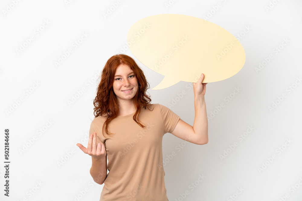Teenager redhead girl isolated on white background holding an empty speech bubble and doing coming gesture Teenager redhead girl isolated on white background holding an empty speech bubble and doing coming gesture