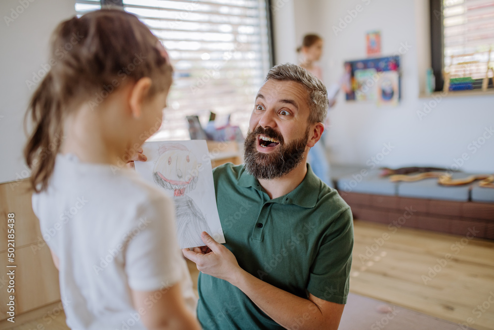 Happy father getting drawings from his little daughter at home. Happy father getting drawings from his little daughter at home.