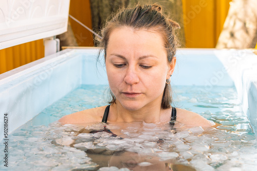 Girl or woman bathing in the cold water among ice cubes. Wim Hof Method, cold therapy, breathing techniques, yoga and meditation