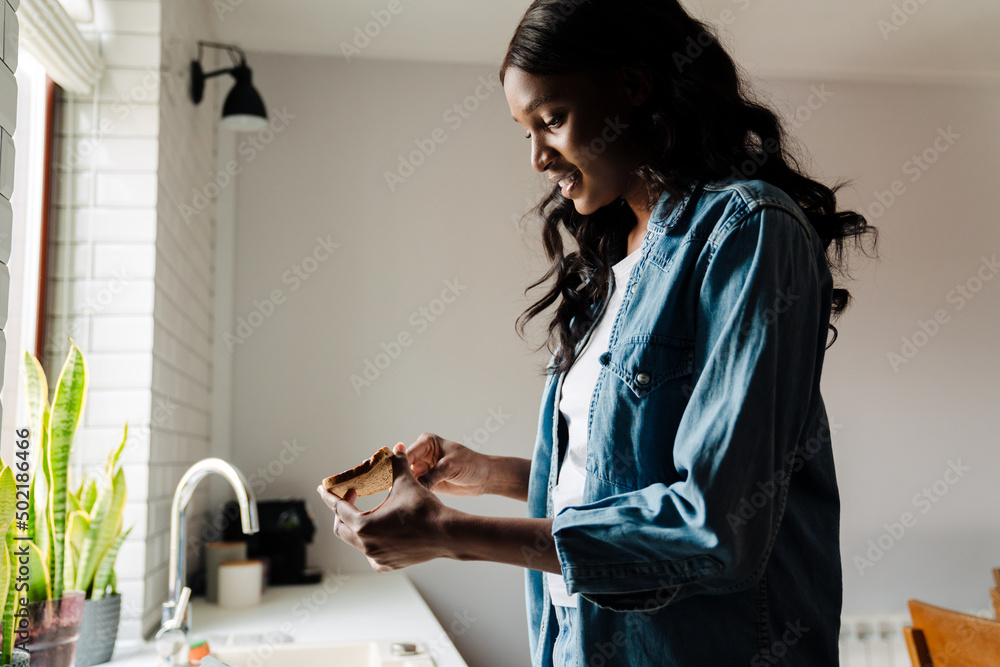 Black young woman smiling while cooking in kitchen