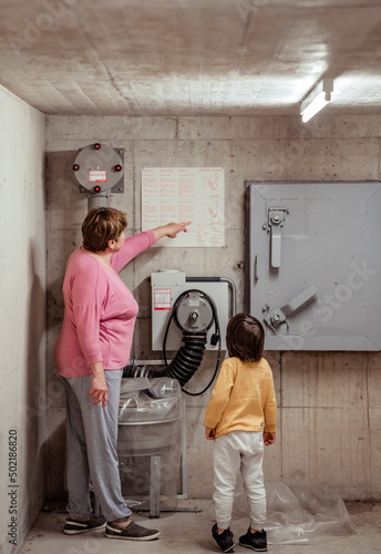 Canvastavla Senior woman with little child in nuclear fallout shelter built in basement of b