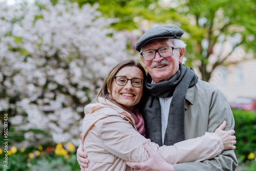 Adult daughter hugging her senior father outdoors in park on spring day. © Halfpoint