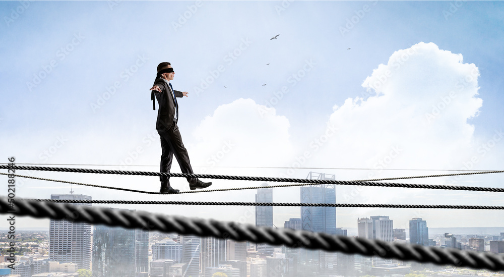 Image of businessman balancing on rope. Risk concept . Mixed media