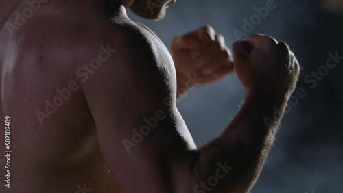 Punches close up in smoke dark background. Muscular kickbox or muay thai fighter punching in smoke.