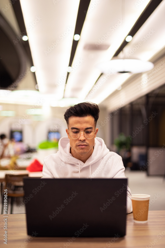 Obraz premium Portrait of handsome young cool man using laptop at coffee shop