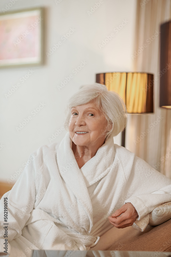 A good-looking old lady in a white robe in a hotel room A good-looking old lady in a white robe in a hotel room