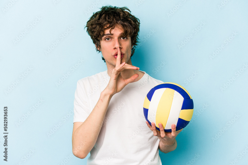Young caucasian man playing volleyball isolated on blue background keeping a secret or asking for silence.
