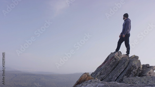 Man on top of the mountain. A young, athletic man stands on a high rock