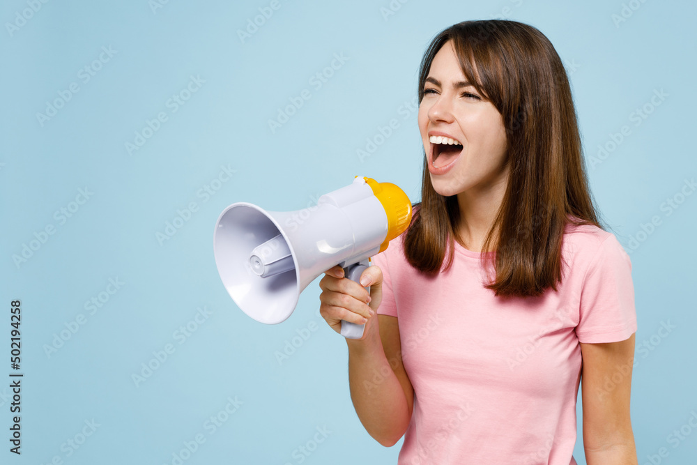 Young caucasian woman 20s wear pink t-shirt hold scream shout in megaphone announces discounts sale Hurry up isolated on pastel plain light blue background studio portrait. People lifestyle concept Young caucasian woman 20s wear pink t-shirt hold scream shout in megaphone announces discounts sale Hurry up isolated on pastel plain light blue background studio portrait. People lifestyle concept