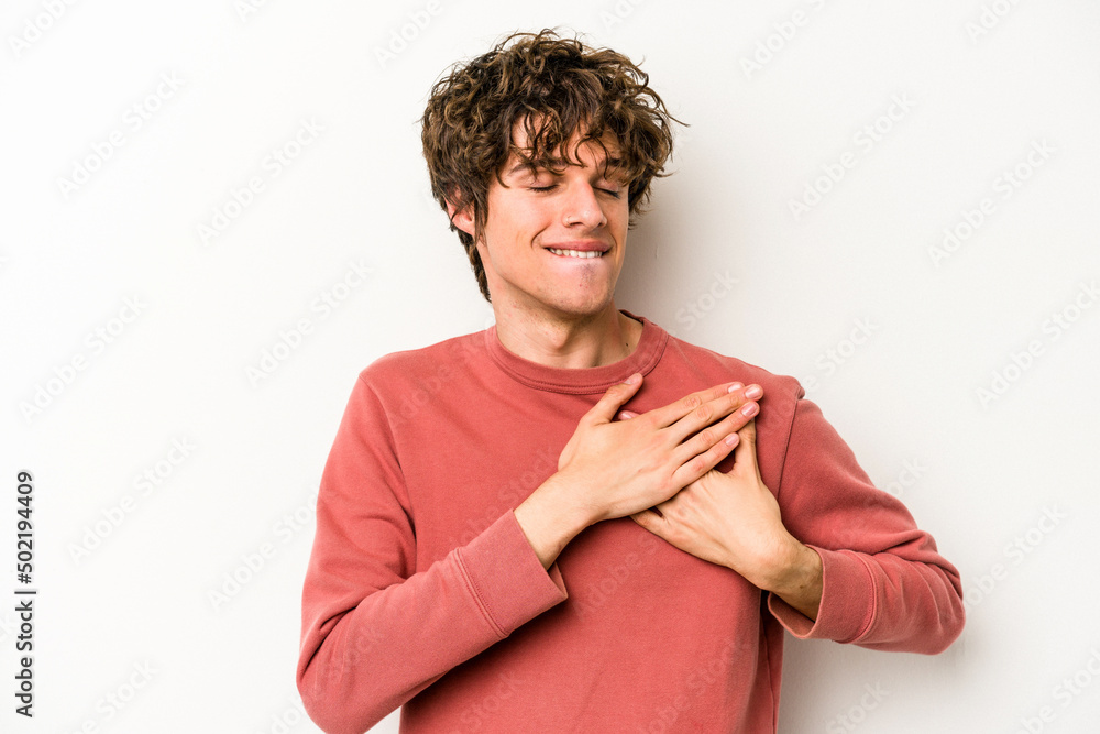 Young caucasian man isolated on white background has friendly expression, pressing palm to chest. Love concept. Young caucasian man isolated on white background has friendly expression, pressing palm to chest. Love concept.