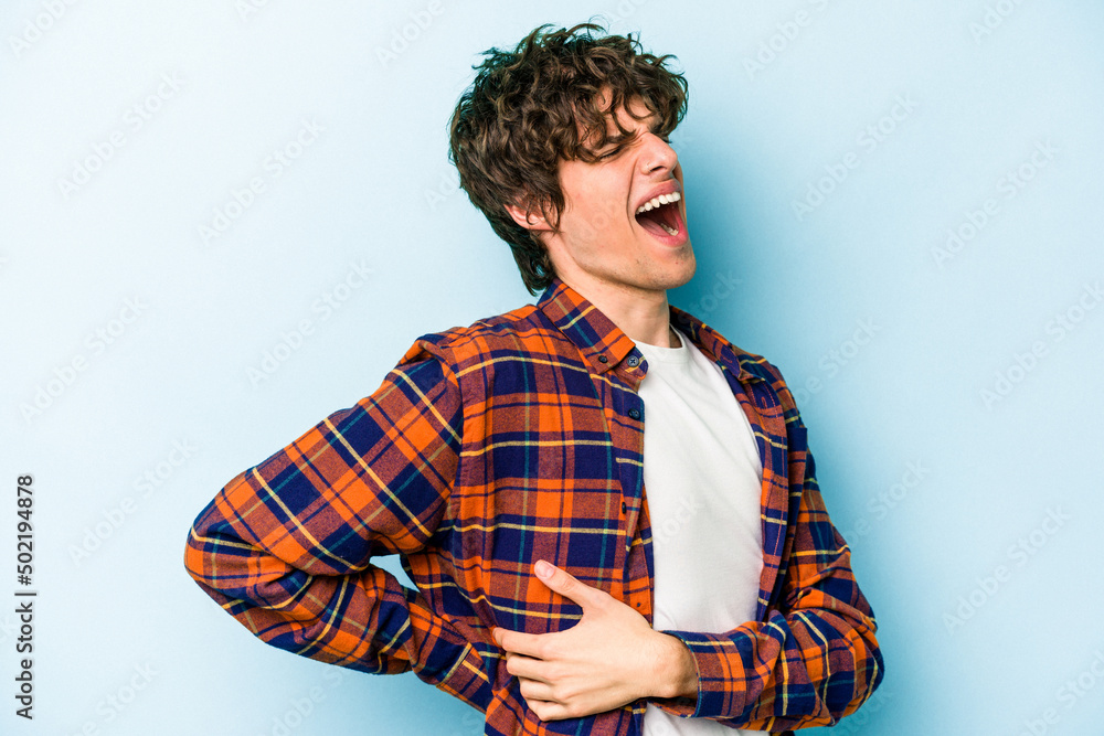 Young caucasian man isolated on blue background suffering a back pain. Young caucasian man isolated on blue background suffering a back pain.