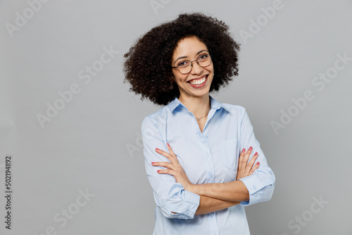 Young fun employee business corporate lawyer woman of African American ethnicity in classic formal shirt work in office hold hands crossed folded look camera isolated on grey color background studio.