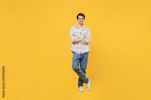 Full body young smiling happy cheerful caucasian man 20s wearing white casual shirt hold hands crossed folded look camera isolated on plain yellow background studio portrait. People lifestyle concept.