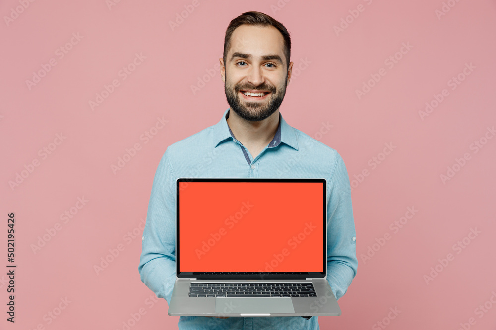 Young fun caucasian man 20s in classic blue shirt hold use work on laptop pc computer with blank screen workspace area isolated on plain pastel light pink background studio. People lifestyle concept Young fun caucasian man 20s in classic blue shirt hold use work on laptop pc computer with blank screen workspace area isolated on plain pastel light pink background studio. People lifestyle concept