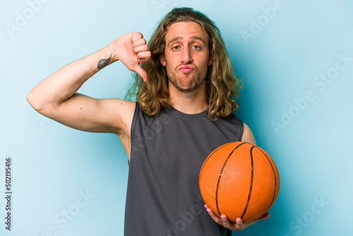 Young caucasian man playing basketball isolated on blue background showing a dislike gesture, thumbs down. Disagreement concept.