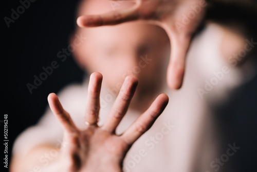 Studio portrait through the fingers of a bald man with a beautiful beard on a black background