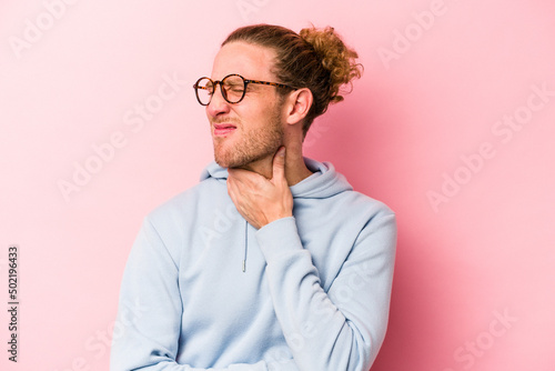 Young caucasian man isolated on pink background suffers pain in throat due a virus or infection.