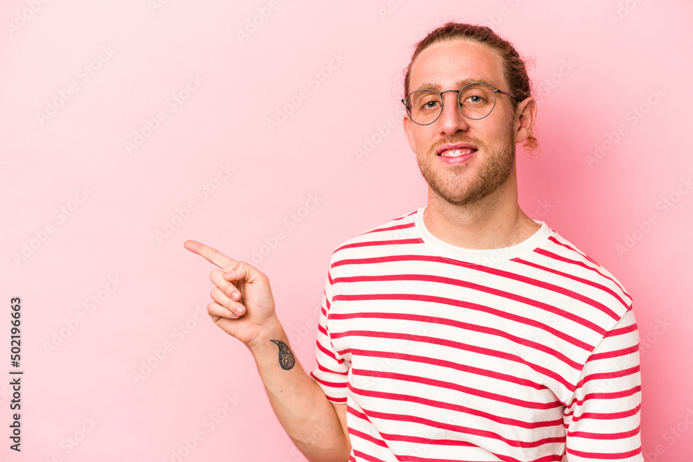 Fototapeta premium Young caucasian man isolated on pink background smiling cheerfully pointing with forefinger away.