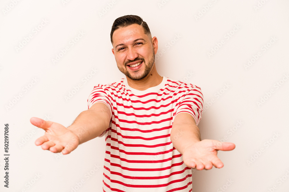 Young hispanic man isolated on white background showing a welcome expression. Young hispanic man isolated on white background showing a welcome expression.