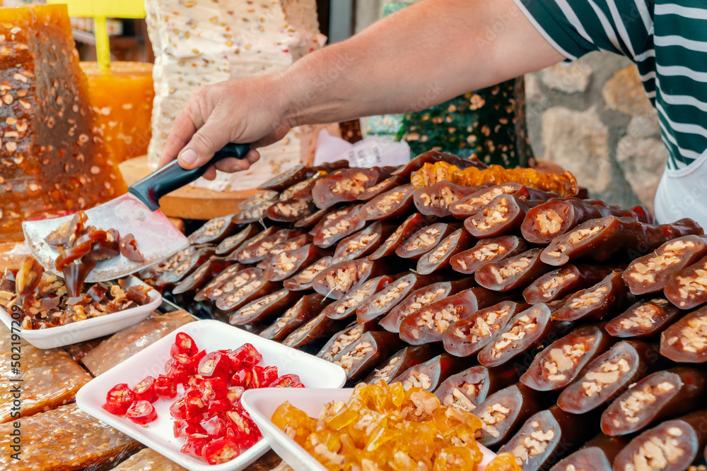 Obraz premium Traditional famous Turkish sweet Walnut Sausage | Cevizli sucuk and Paste with walnut | Cevizli pestil on a showcase in a food shop in bazaar. Turkish dried fruit pulp with walnut