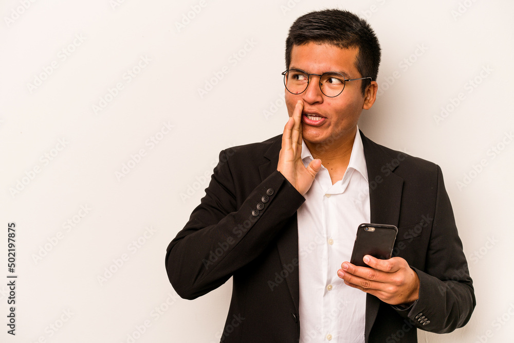 Young business hispanic man holding mobile phone isolated on white background is saying a secret hot braking news and looking aside Young business hispanic man holding mobile phone isolated on white background is saying a secret hot braking news and looking aside