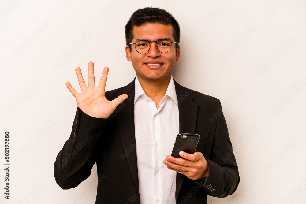 Young business hispanic man holding mobile phone isolated on white background smiling cheerful showing number five with fingers. Young business hispanic man holding mobile phone isolated on white background smiling cheerful showing number five with fingers.
