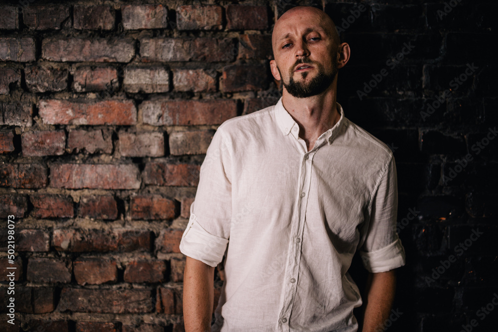 Portrait of a bald man with a beautiful beard in a white shirt on a brick background Portrait of a bald man with a beautiful beard in a white shirt on a brick background